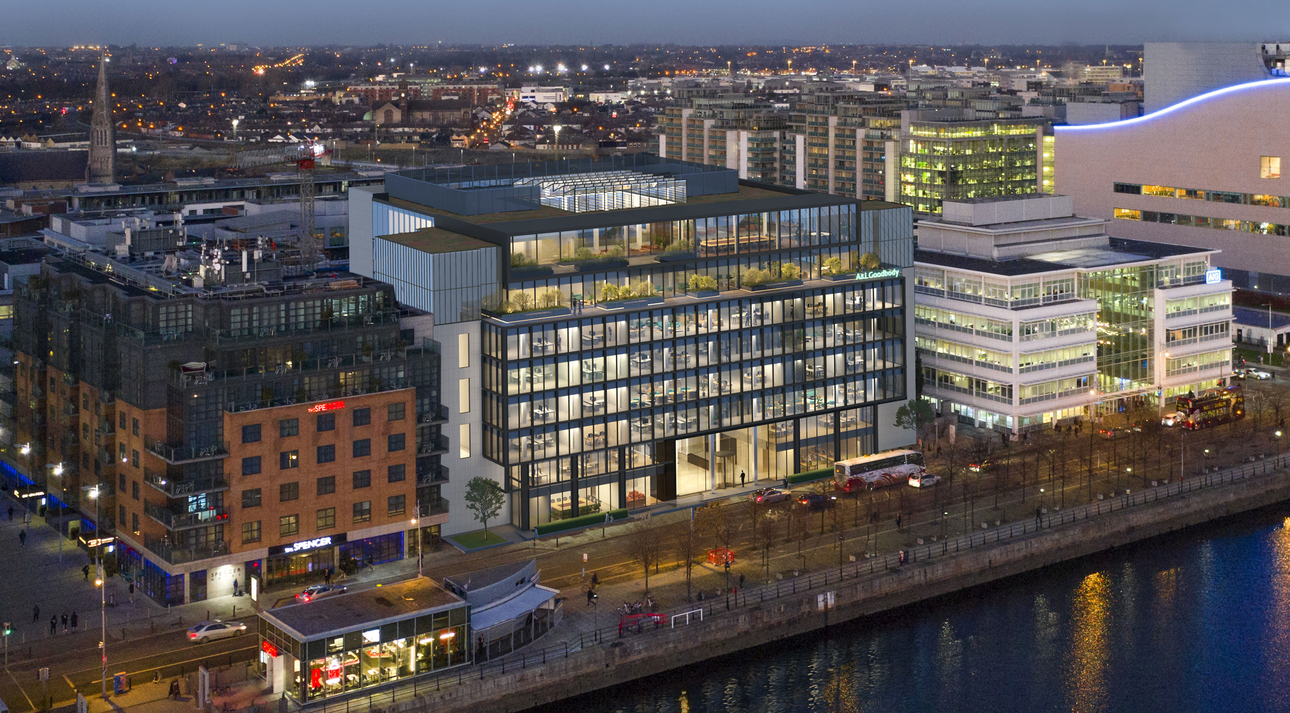 The Dublin docklands at dusk, with lit riverside office buildings along the quays.